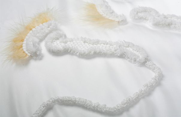 White Textile Piece With Feather Details Soft white textile piece with printed elements and feather details